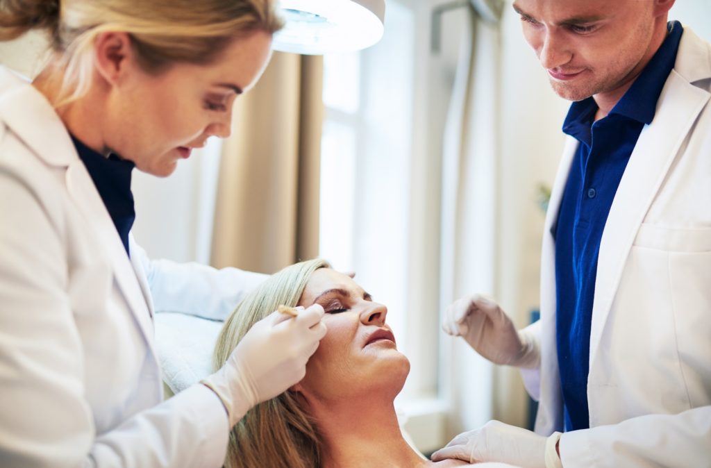 Two doctors planning surgery options together over a female client